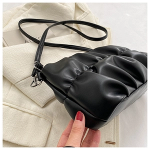 Detail of black pleated cloud bag texture with leather strap and metal buckle