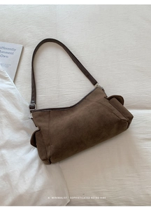 Detail of dark brown suede shoulder bag with side pocket and sleek leather strap