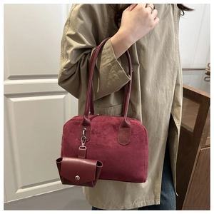 Detail of burgundy baguette bag with suede texture and hanging mini coin purse charm