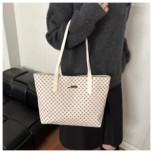 Detail of beige tote bag with brown geometric pattern worn by a model in winter outfit