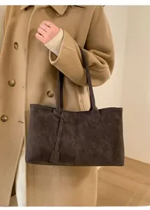 Detail of dark brown suede tote bag featuring vertical stitching and a matching decorative tag