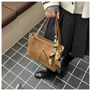 Detail view of brown leather tote bag with white contrast stitching and silk scarf wrap