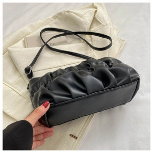 Close-up of black pleated cloud bag texture and silver metal strap adjustment buckle