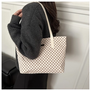 Detail of classic beige tote bag with brown geometric pattern worn by a model