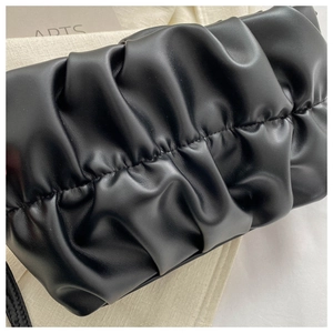 Close-up detail of the luxury black pleated handbag with a premium glossy finish