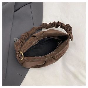 Detail view of brown pleated cloud bag featuring soft texture and gold metal ring accent