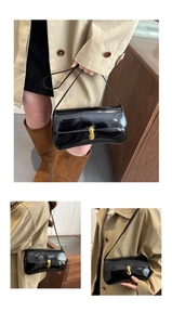 Close-up of retro black patent leather shoulder bag featuring a gold U-shaped metal lock