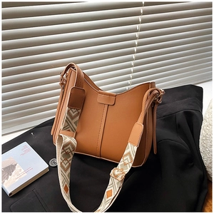 Close-up of caramel brown leather hobo bag with a geometric pattern wide shoulder strap