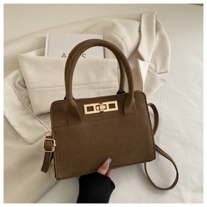 Detail of dark brown frosted suede handbag with elegant golden metal twist lock closure