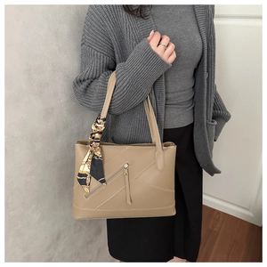Detail of tan tote bag featuring diagonal stitching and decorative silk scarf handle