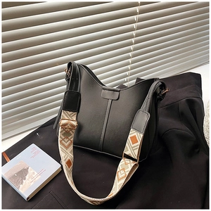 Detail of hobo bag showing textured geometric woven wide strap and matte leather finish