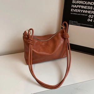 Minimalist brown PU leather tote bag with unique knotted strap on marble surface