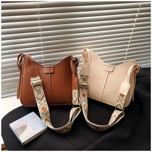 Close-up of brown and cream shoulder bags featuring wide geometric jacquard straps