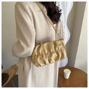 Detail view of yellow ruched shoulder bag with adjustable strap and silver metal hardware