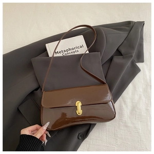 Detail view of a vintage brown patent leather shoulder bag with a gold metal clasp