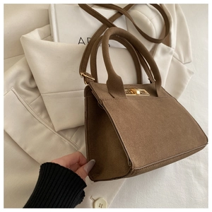 Detail view of brown matte leather handbag with gold hardware and removable strap