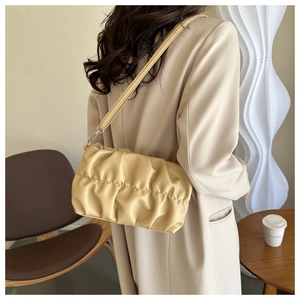 Close-up of cream pleated shoulder bag showing soft PU leather texture and silver hooks