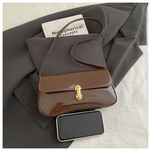 Close-up of brown patent leather shoulder bag with gold metal buckle and glossy finish