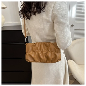 Detail view of caramel brown pleated shoulder bag with silver metal rings on model