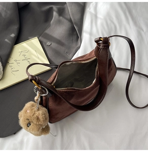 Top view of a brown suede shoulder bag with gold zipper and a cute teddy bear charm