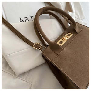 Detail of vintage matte brown leather handbag with gold metal lock and fine stitching