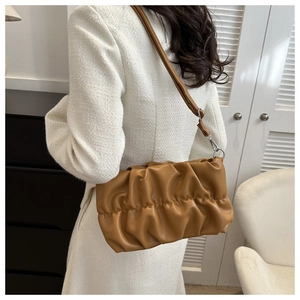 Detail of caramel pleated shoulder bag showing soft leather texture and silver hardware