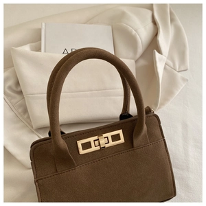 Close-up of a vintage brown matte leather handbag with a rectangular gold twist-lock