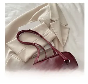 Close-up of deep red glossy leather shoulder bag with contrasting white stitching and pocket