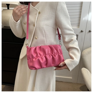 Detail of a pink ruched crossbody bag with leather texture and slim shoulder strap