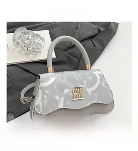 Close-up of grey textured handbag with wavy flap and gold logo buckle detail