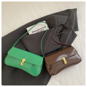 Glossy patent leather shoulder bags with gold U-shaped buckles on a tailored blazer