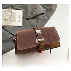 Detail of mixed textures featuring matte suede flap and shiny patent leather on brown bag