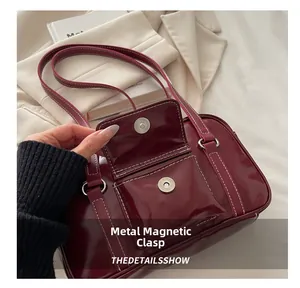 Close-up of wine red leather bag showing magnetic clasp and contrast stitching detail