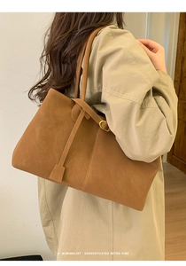 Close-up of brown suede tote bag featuring a minimalist retro vibe on a beige trench coat