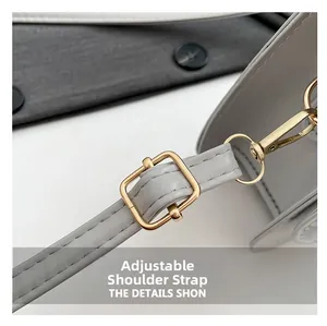 Detail of adjustable light grey leather shoulder strap with gold metal buckle and lobster clasp