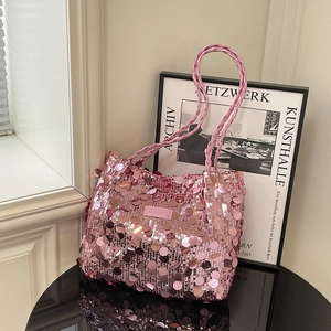 Pink sequin tote bag with woven handles on a sleek reflective surface for 2025 fashion