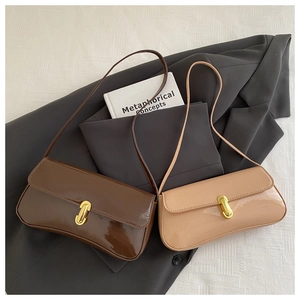 Detailed view of glossy patent leather shoulder bags with gold twist locks and books