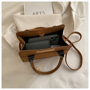 Internal view of brown matte handbag showing space for wallet, phone and headphones