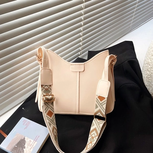 Minimalist beige shoulder bag with vintage geometric woven wide strap on a blazer