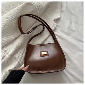 Détail du sac vintage en cuir PU marron avec plaque dorée et coutures de précision