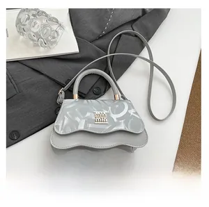 Close-up of light gray leather handbag with wavy flap edge and gold lettering logo