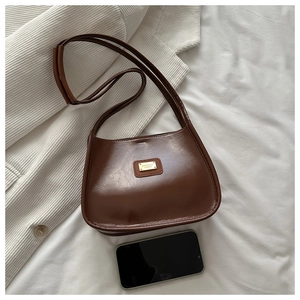 Vue détaillée d'un sac à main en cuir PU marron foncé avec plaque dorée et un smartphone