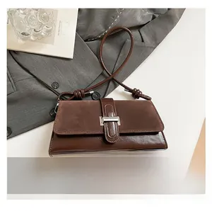 Close-up of vintage brown suede baguette bag with knotted strap and metal buckle