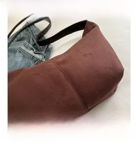 Close-up of dark brown suede shoulder bag featuring double-line stitching and minimalist style