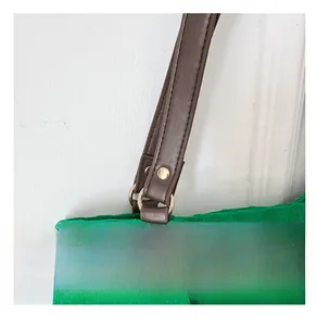 Dettaglio della borsa tote verde in tela con tracolla in pelle marrone e metallo dorato