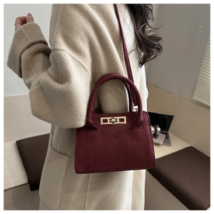 Dettaglio della borsa bordeaux in camoscio con chiusura in metallo dorato su cappotto beige