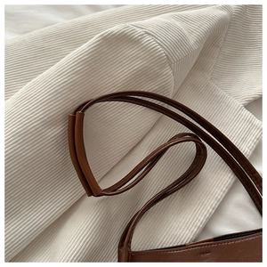 Détail de la fine bandoulière en cuir marron avec coutures renforcées et texture délicate