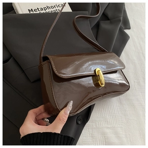 Close-up of shiny dark brown patent leather bag with premium gold metal clasp detail