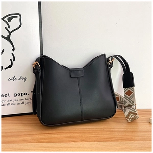 Minimalist black leather crossbody bag with curved edge and patterned wide shoulder strap