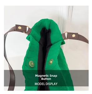 Dettaglio della chiusura magnetica su una borsa trapuntata verde con manici in pelle